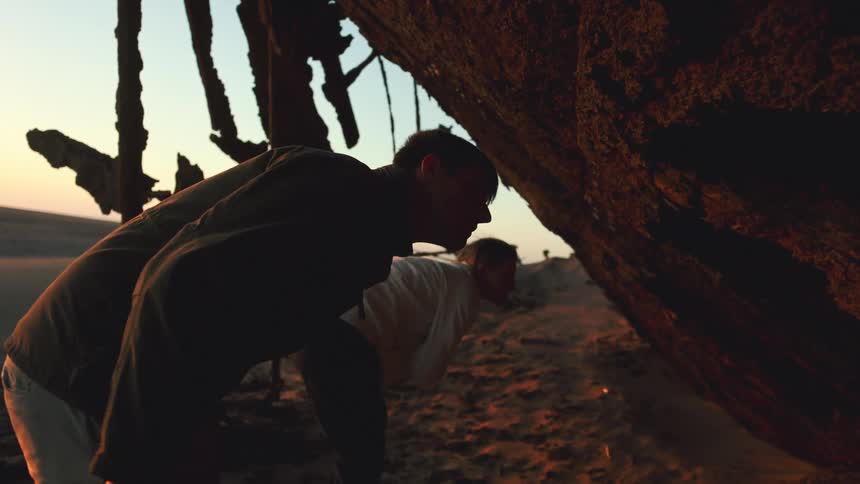 Man and woman explore desert ship wreck up close