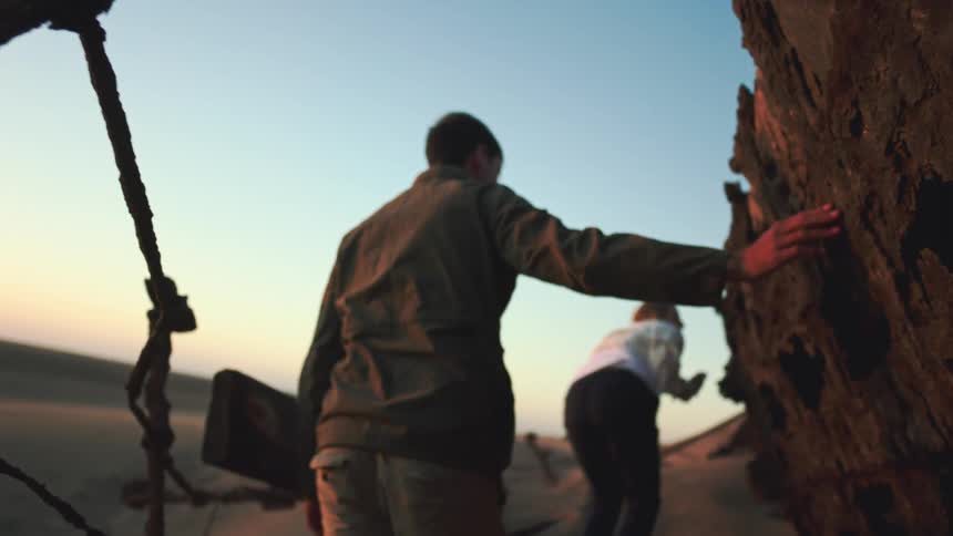 Man and woman walk through amazing desert shipwreck