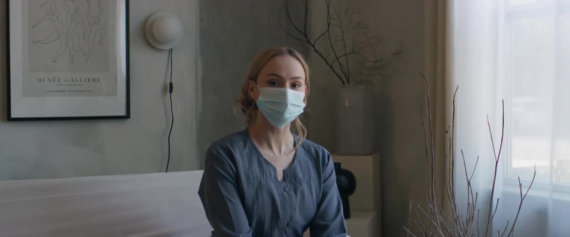 Woman wearing a face mask sits near window