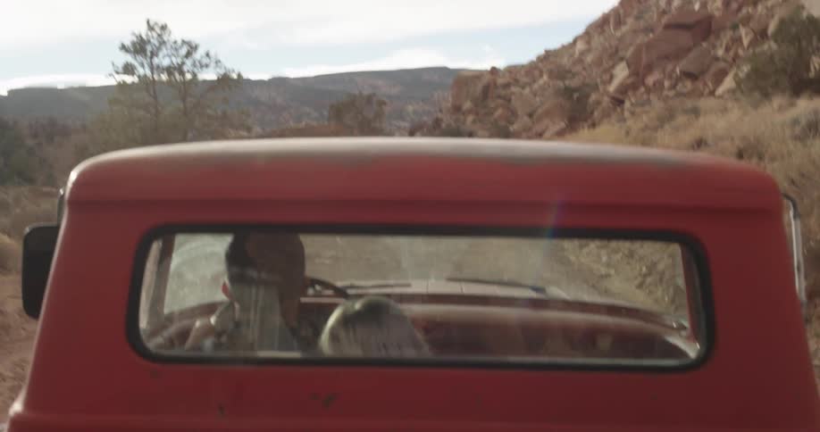 A woman leaning her head on a man's shoulder as he drives along a mountain road