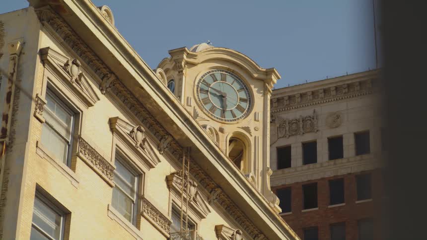 A clock tower atop a building in a city during the day