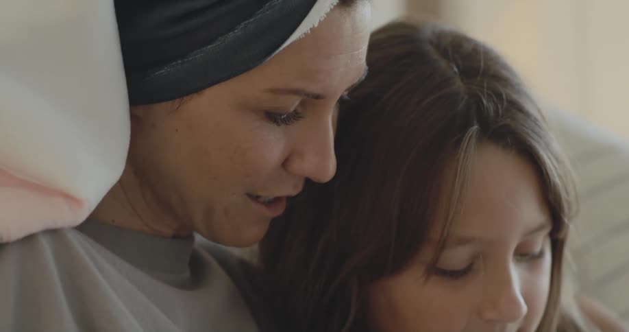 Woman hugs sits hugging girl as she read to her