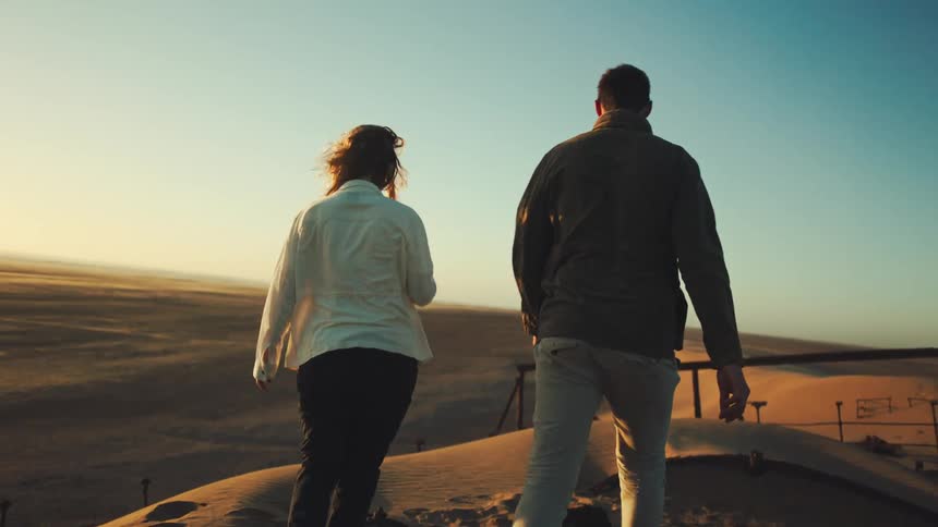 Man and woman explore peaceful desert terrain at sunset
