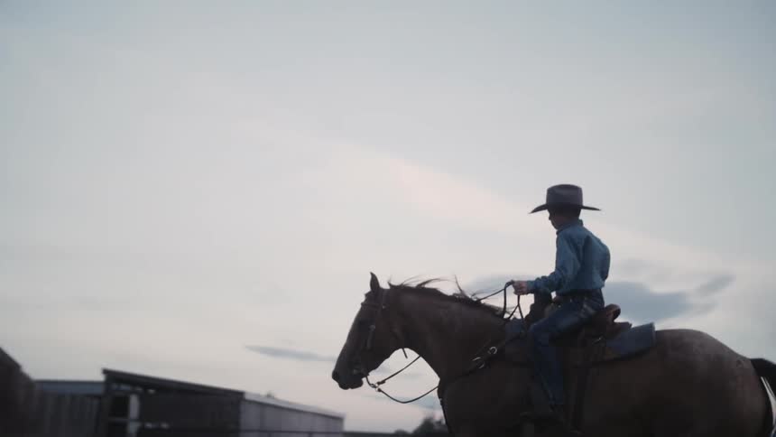 A boy is riding a horse on a ranch