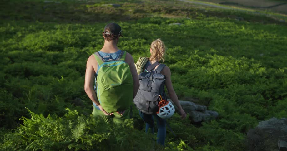 A man and woman hike down a hill