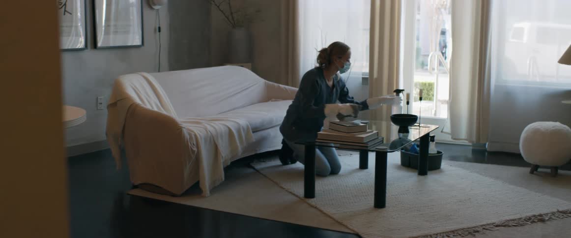 Woman with mask ponytail blue shirt and jeans cleans bowl in living room athome
