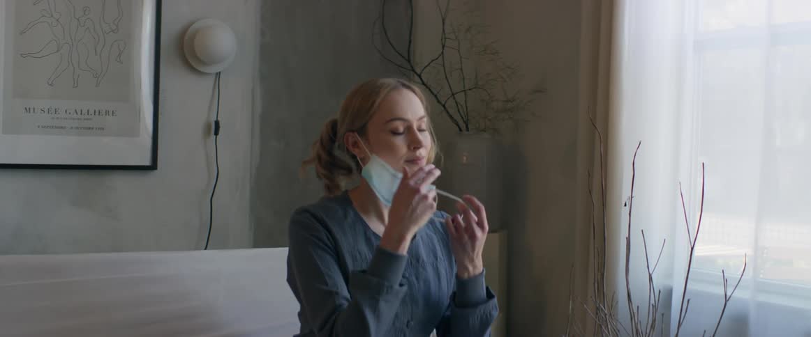 A woman takes off her mask inside