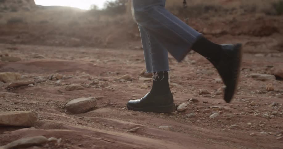 Person walking a rocky dirt path at sunset