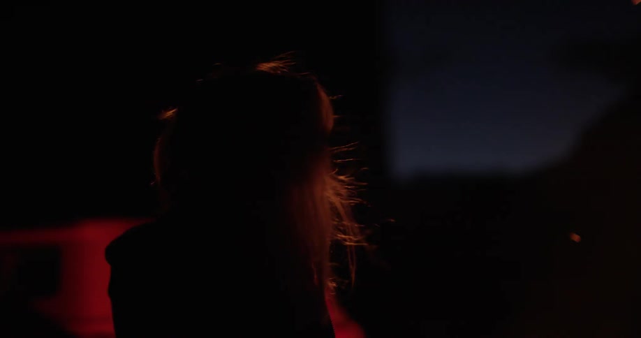 Woman standing near fire on a windy night