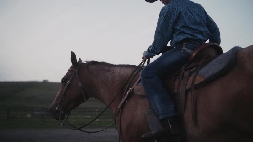 A young cowboy rides a horse during the day