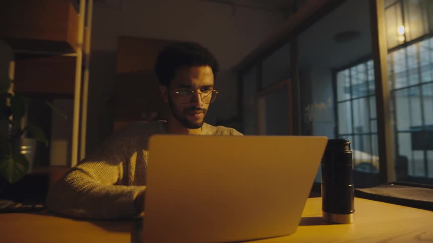 timelapse of man typing on a laptop while occasionally drinking from a thermal mug