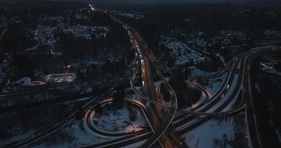 Traffic flows along a snowy highway interchange during the evening commute