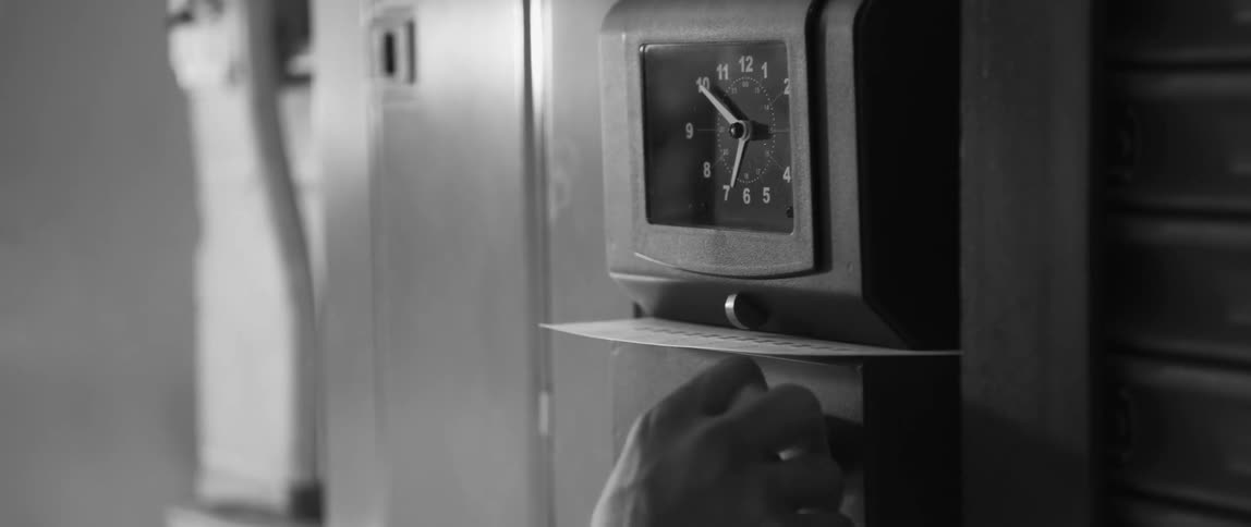 Man puts time card into time clock and pull punch handle