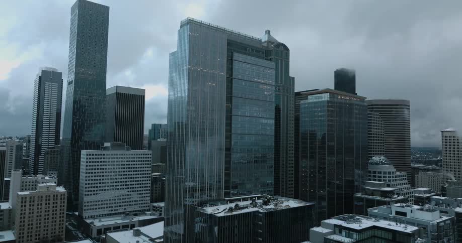 Pullback reveal of tall skyscrapers and city rooftops covered in snow on a gray winter day