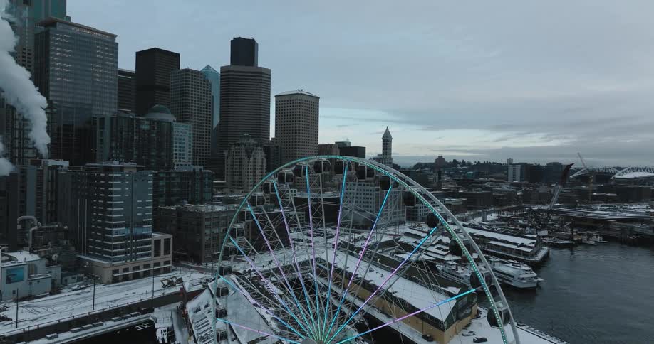Ascending over a Ferris wheel toward downtown buildings on a cold winter day