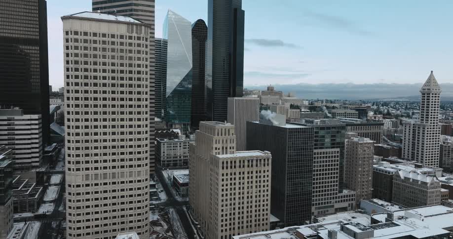 Snow covers the roof of city buildings in front of tall skyscrapers on a cold winter afternoon