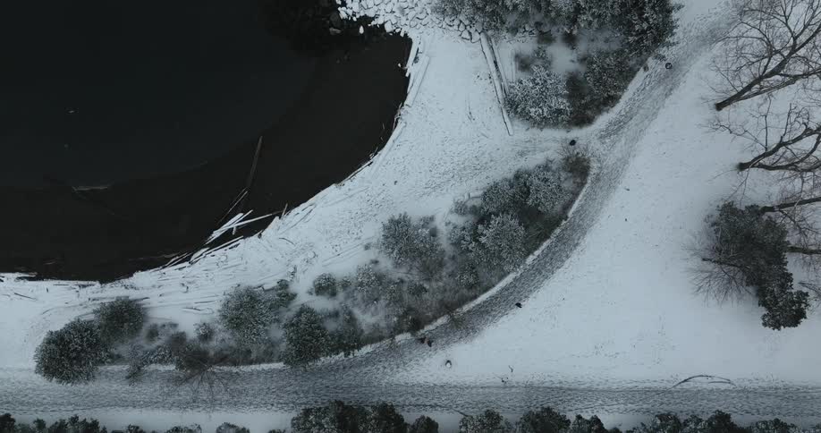 Top down view of pedestrians walking on a snowy path in a city park