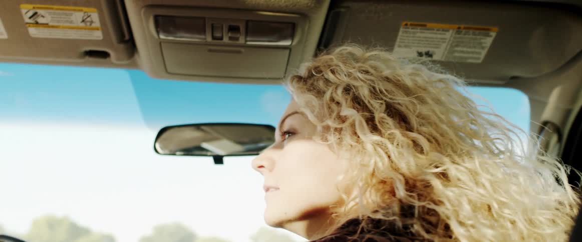 A woman who is a passenger in a car looks around