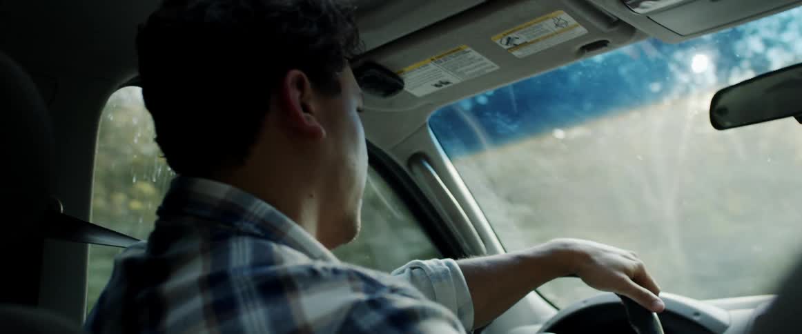 A man talks to a passenger while driving a vehicle