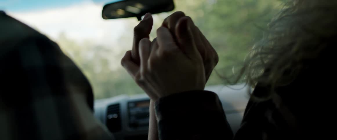Couple sitting in moving vehicle hold hands