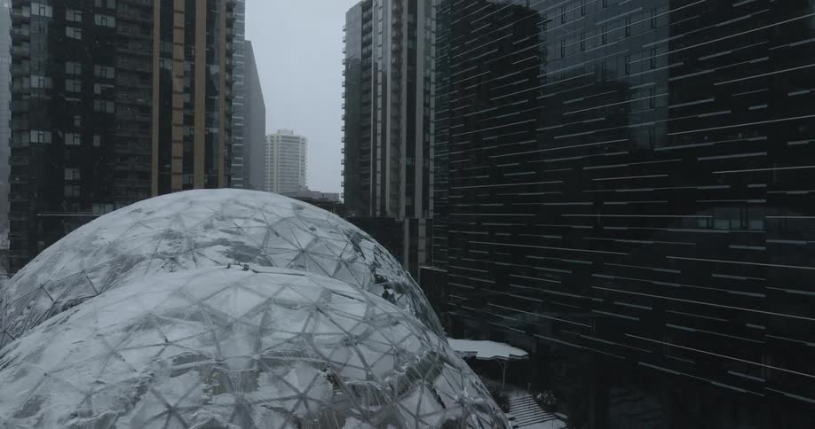 Low reveal of the Amazon Spheres conservatories and office complex covered in snow during a winter storm