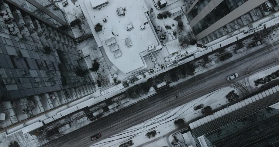 Top down traverse between apartment towers as snow falls gently onto city streets below