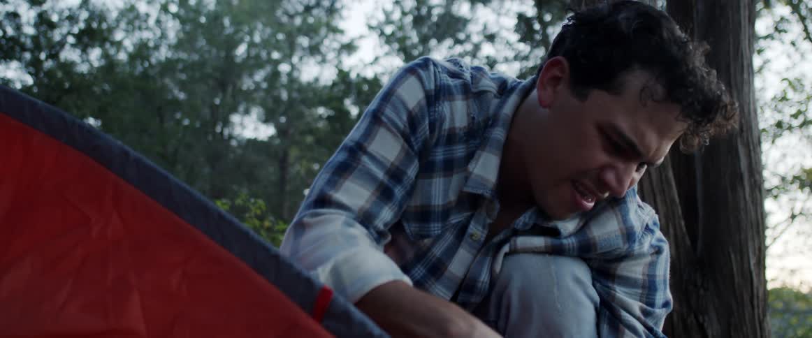 Man works putting together tent with canvas parts in woods