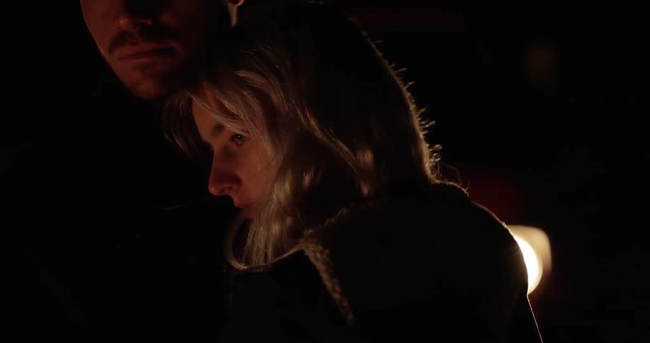 A woman is leaning on a man at night