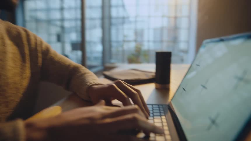 Young man sitting at a desk working on a laptop with a white replaceable screen
