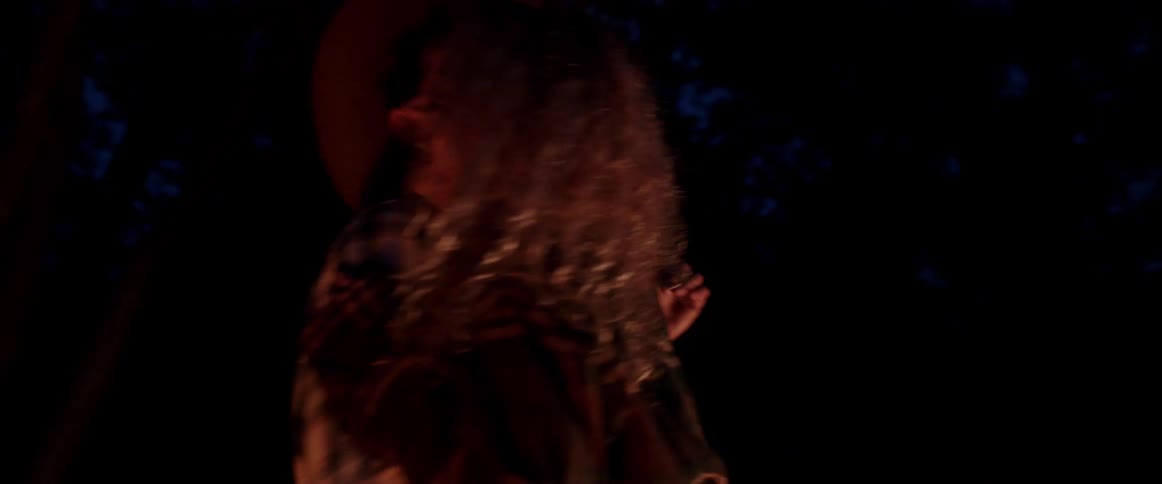 A man and woman laugh as they dance outside at night