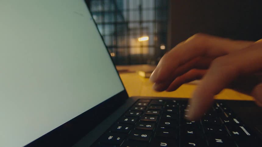 camera moves through hands and fingers typing on a laptop keyboard slower