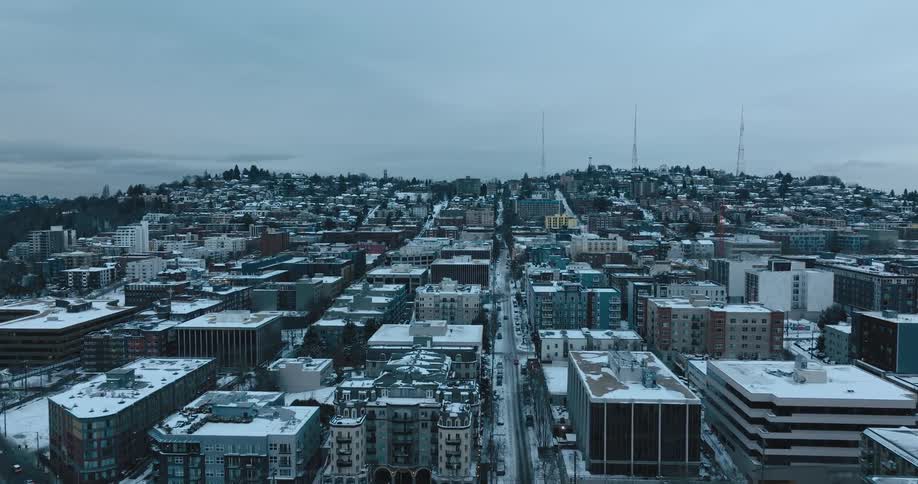 Aerial traverse over snow covered roads and apartment buildings of an urban neighborhood