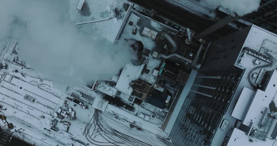 Steam rises into the cold winter air from the smoke stacks on the roof of a building