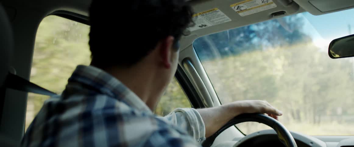 Male driver shakes his head in response to his passenger as he drives