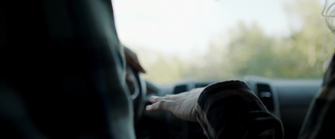 Young blonde woman sitting on the passenger seat of a driving car waving her hands