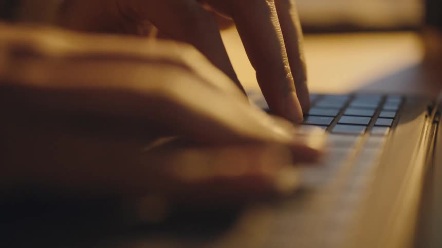 A persons hands and fingers typing on a keyboard