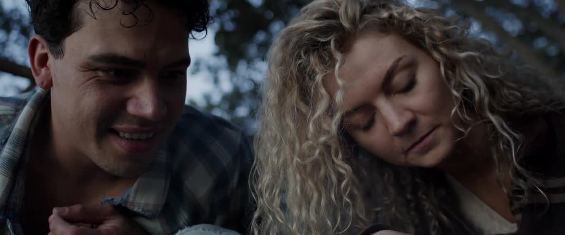 Young couple talking while crouching on the forest floor at morning