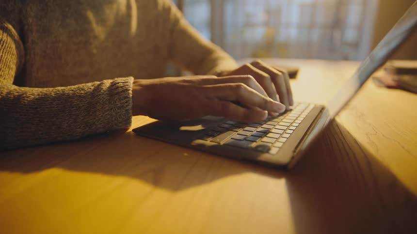 person sitting at a table typing on a laptop computer