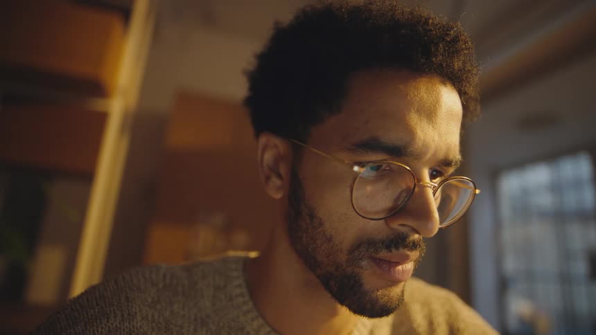 man with a beard and wearing glasses works reads concentrated and then smiles satisfied