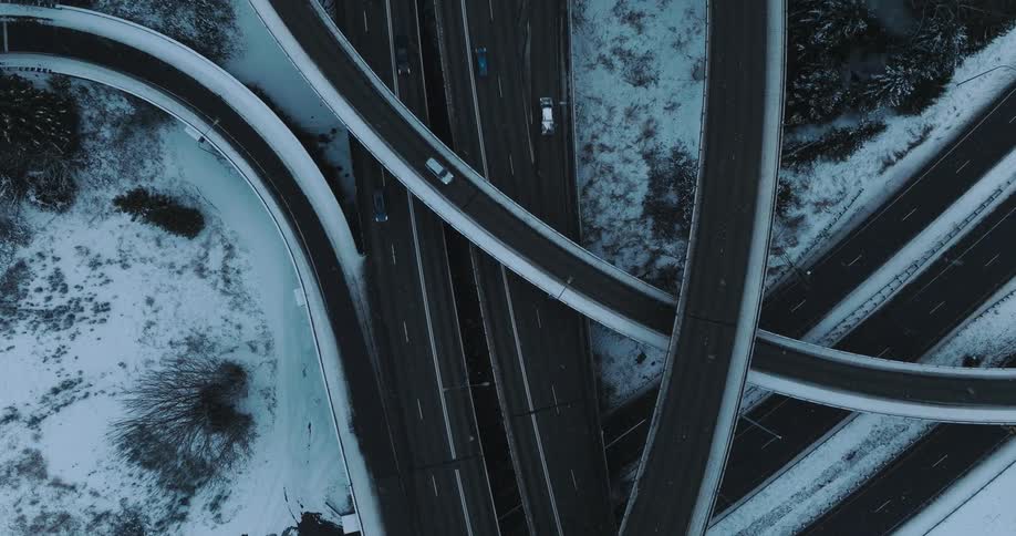 Birds eye view of vehicles driving on a slush covered highway as snow falls