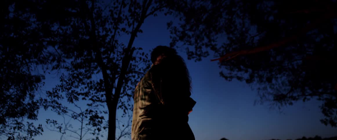 Couple slow dances outdoors in woods at night