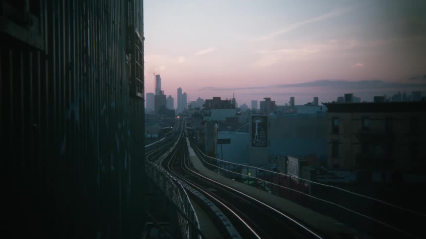 Empty train tracks running into the city next to a lake at dusk