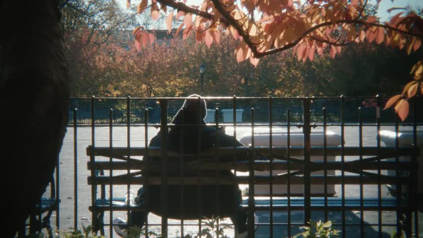 A man sits on a park bench and smokes a cigarette