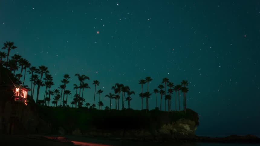 Starry sky at night over the building and palm trees