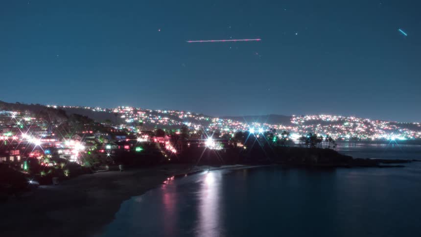 Speed up time lapse of planes taking off an airport on a small coastal town at night