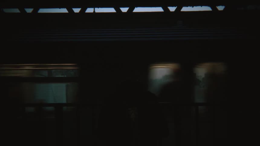A man stands at a train station and a train pulls up and he gets on