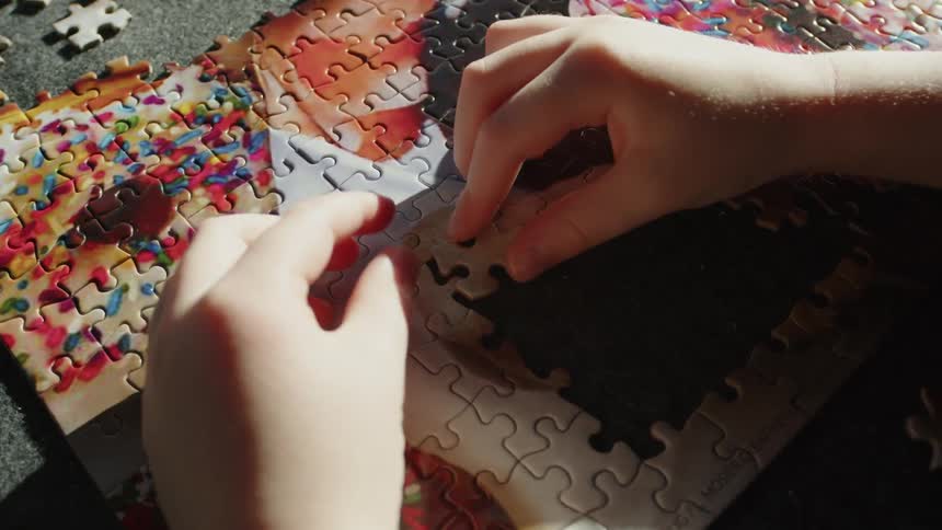 A child places a puzzle piece into a jigsaw puzzle