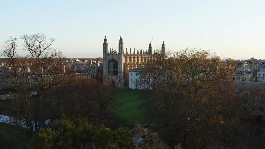 Reveal from behind trees aerial of Kings College Chapel in Cambridge