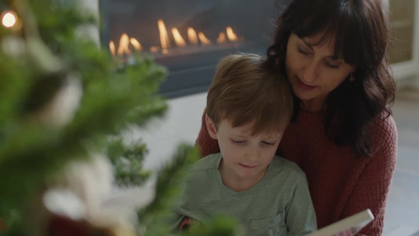 Woman holds a little boy on her lap and reads him a book