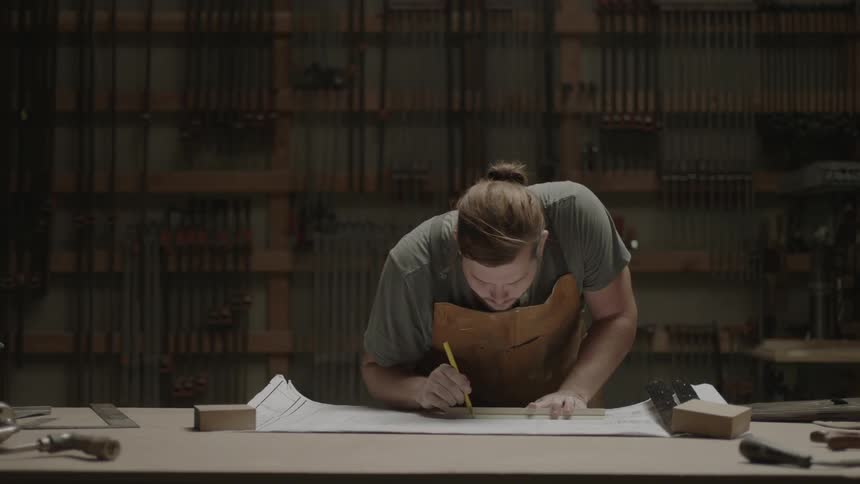 A man rolls out a diagram and makes some marks with a ruler